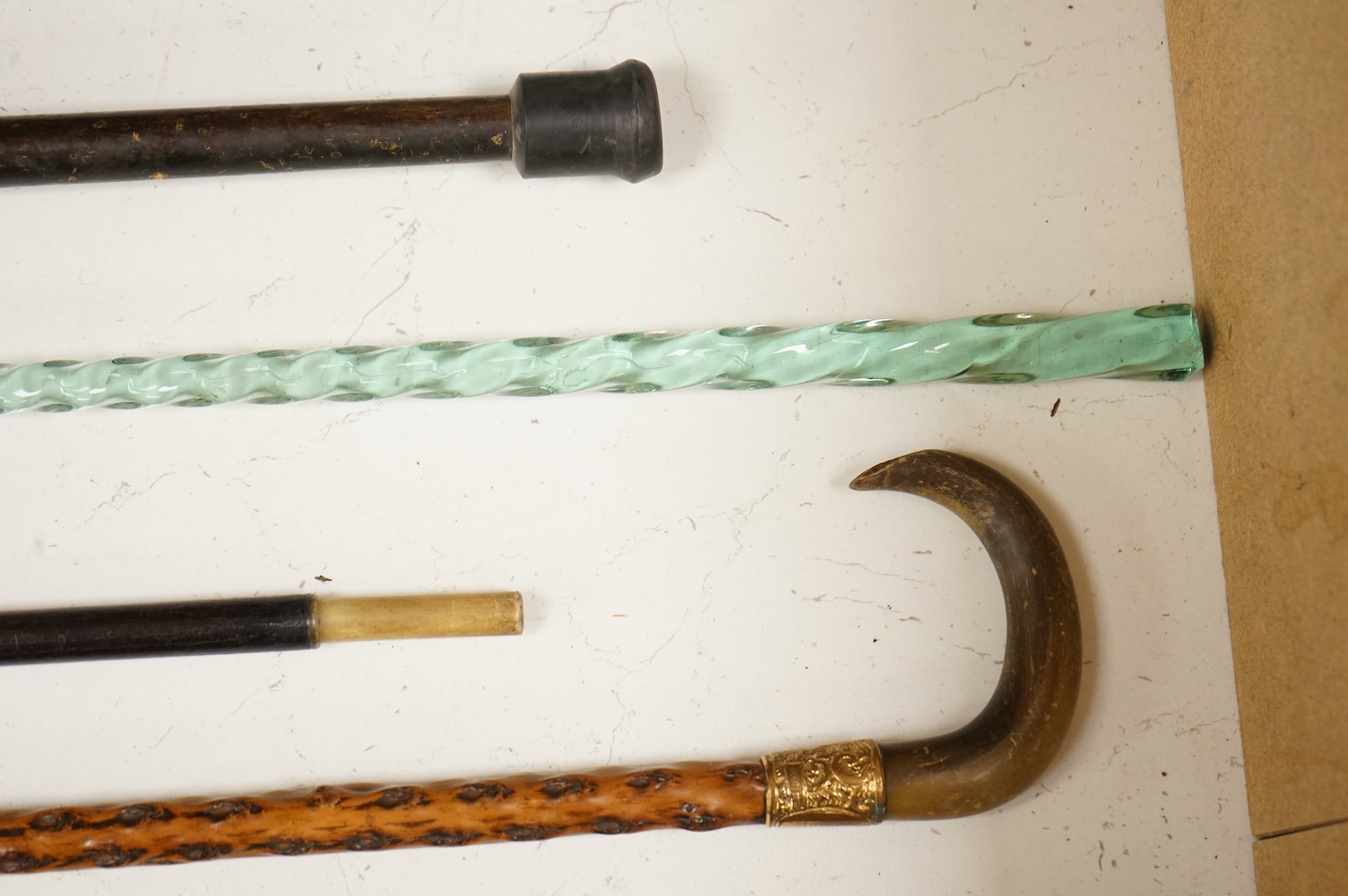 Four walking sticks to include a Brigg of London with carved horn handle in the form of a dogs head and a barley twist glass example, largest 123cm in length